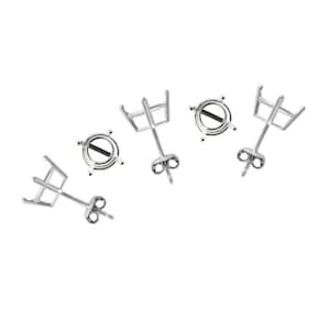 May include: Four silver earring settings with prongs for holding a gemstone. Each setting has a round bezel and a post with a butterfly back.