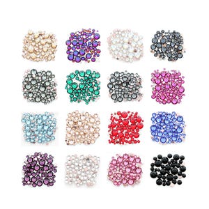 May include: A collection of sixteen clusters of round, faceted rhinestones arranged in a grid. The sets feature various colours including gold, purple, iridescent white, dark grey, green, black, pink, light blue, beige, red, and royal blue.