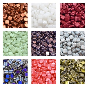 Könnte beinhalten: Sortiment an quadratischen Glasperlen in verschiedenen Farben, darunter Rot, Weiß, Grün, Lila, Blau, Rosa und Gold. Die Perlen sind alle gleich groß und gleich geformt und in einem Raster angeordnet.
