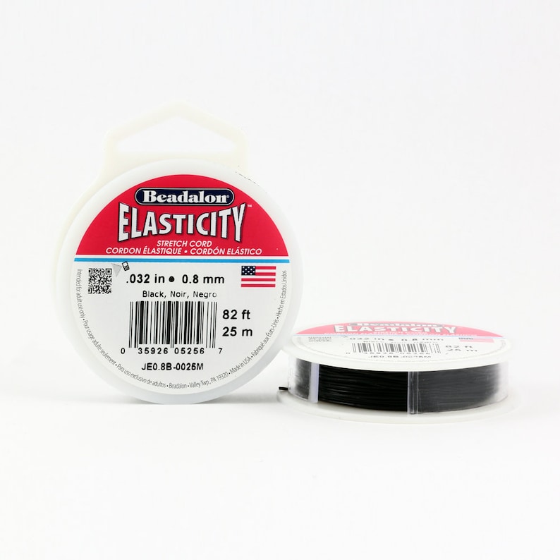 Może przedstawiać: Szpula czarnego elastycznego sznurka Beadalon Elasticity, o średnicy 0,8 mm, długości 25 metr&oacute;w. Etykieta zawiera napis "Beadalon Elasticity Stretch Cord Cordon Elastique Cordon Elastico .032 in 0.8 mm Black, Noir, Negro 82 ft 25 m JE0.8B-0025M"