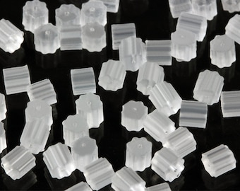 May include: A scattering of translucent earring backs. The earring backs are made of a clear, soft plastic material. The backs have a ribbed design and a small hole in the centre.