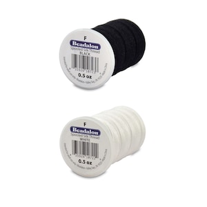 May include: Two spools of Beadalon Spool Silk Thread, one black and one white. Each spool is labeled with the brand name, thread type, color, and weight (0.5 oz).