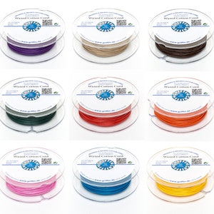 Puede incluir: Nueve carretes de cordón de algodón encerado en varios colores, incluyendo morado, beige, marrón, verde, rojo, naranja, rosa, azul y amarillo. Cada carrete tiene una etiqueta que dice "Waxed Cotton Cord" con un logotipo y una dirección de sitio web.