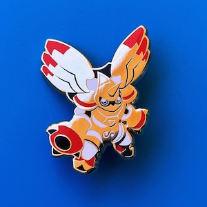 May include: Gold and red enamel pin featuring a cartoon character with wings and a helmet. The character is in a fighting pose with one arm raised and the other holding a weapon.