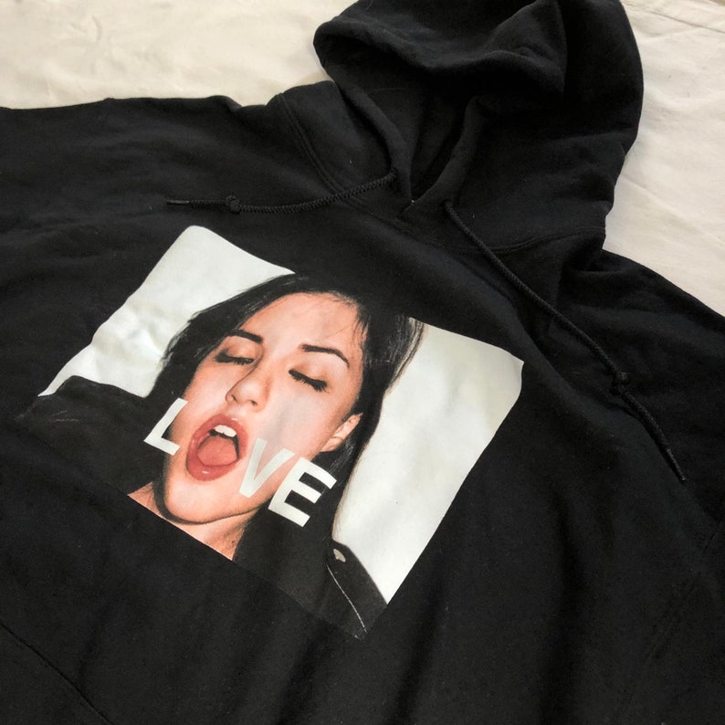 May include: Black hooded sweatshirt with a white graphic print of a woman's face with the word "LOVE" printed upside down.