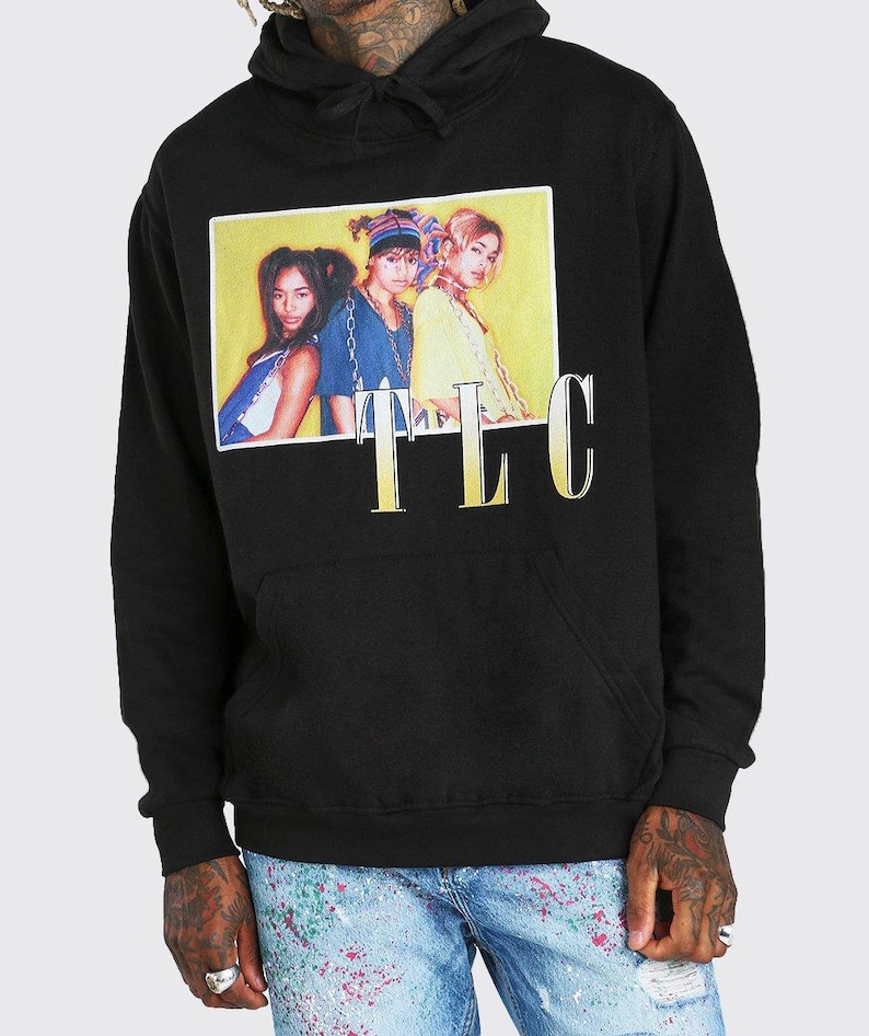 May include: Black hooded sweatshirt with a graphic print of a yellow rectangle with three women in it. The text "TLC" is printed below the rectangle in gold.