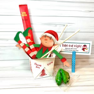 May include: A festive take-out container with an elf figurine, chopsticks, and fortune cookies. The container has the words "Thank You" and "Enjoy" printed on it. A sign reads "Take out night" with an owl illustration.