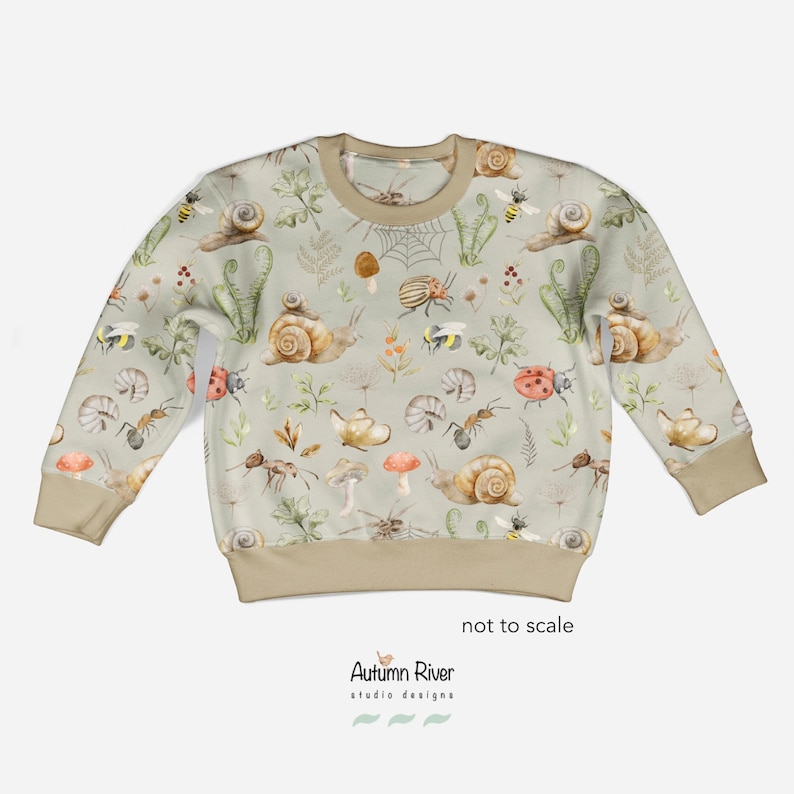 May include: A light green sweatshirt with a pattern of snails, ladybugs, ants, mushrooms, and bees. The text "Autumn River studio designs" is printed on the bottom of the sweatshirt.