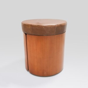 May include: A brown leather-topped wooden stool with a cylindrical shape.