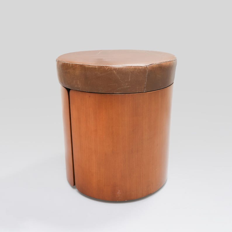 May include: A brown leather-topped wooden stool with a cylindrical shape.