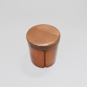 May include: A brown wooden stool with a leather top. The stool is round and has a simple design.