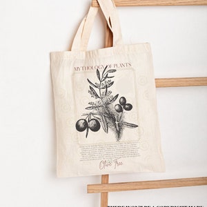 Pode incluir: Uma bolsa de tecido branca com uma ilustra&ccedil;&atilde;o em preto e branco de uma oliveira e o texto "Mythology of Plants" e "Olive Tree". O texto "There won't be a copyright mark on your bag" est&aacute; impresso na parte inferior da bolsa.