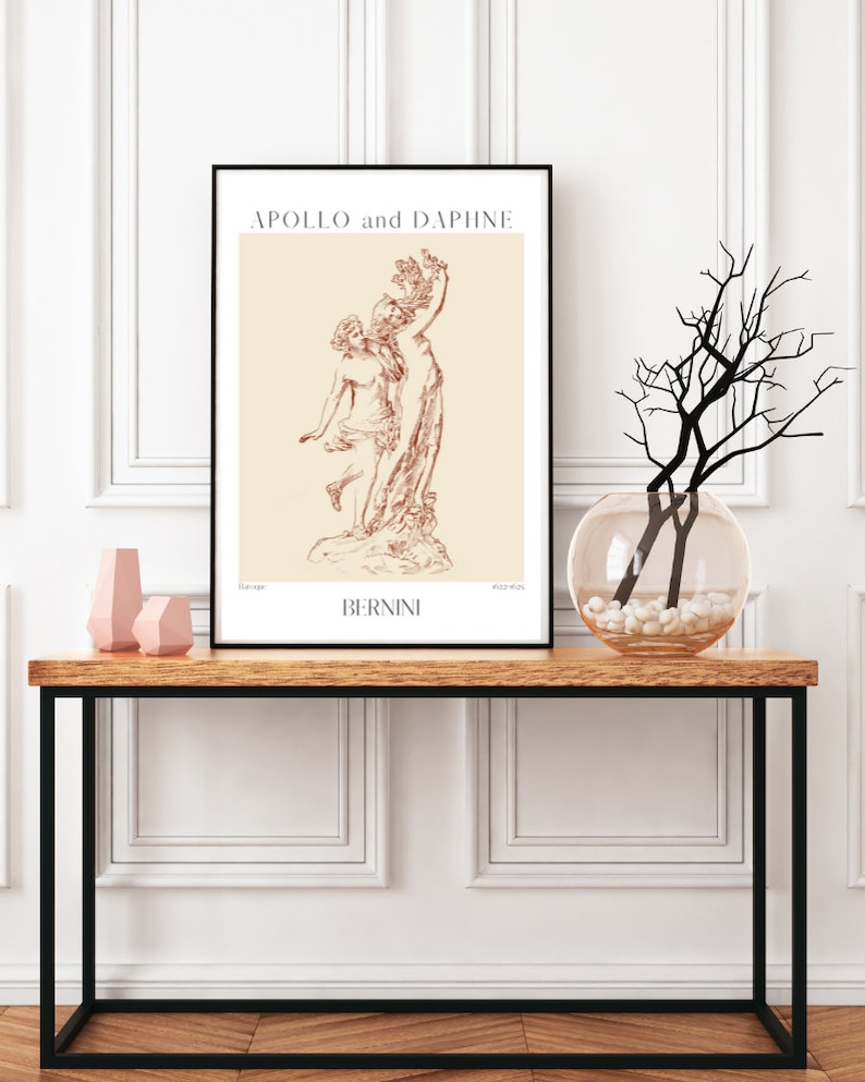 May include: A black framed print of a line drawing of the sculpture "Apollo and Daphne" by Bernini. The print is on a beige background and features the title of the artwork and the artist's name.