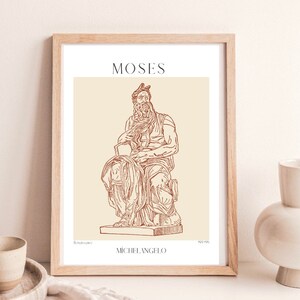 May include: A framed print of a line drawing of the Moses sculpture by Michelangelo. The sculpture is depicted in a seated pose with a beard and a crown. The print is on a beige background with the title "MOSES" and the artist's name "MICHELANGELO" in brown text.
