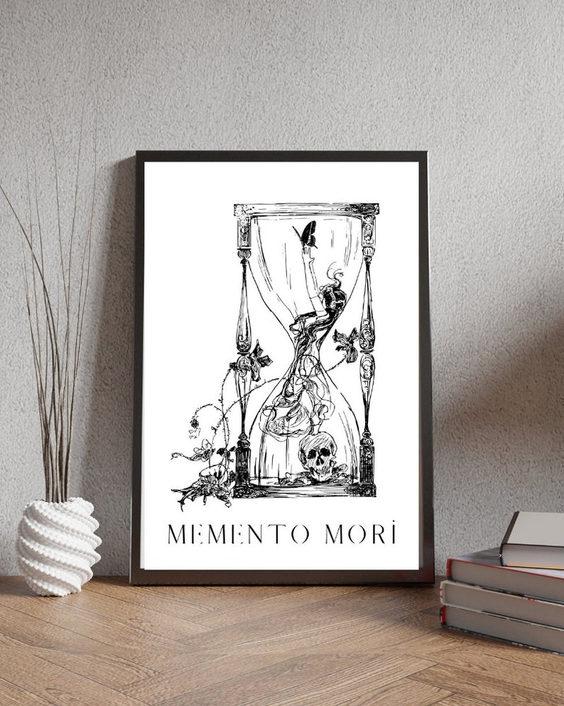 May include: Black and white illustration of an hourglass with a skull at the bottom and a butterfly flying above. The hourglass is surrounded by vines and flowers. The text "MEMENTO MORI" is printed below the hourglass.