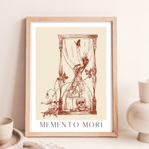 May include: A framed print featuring a red hourglass design. The hourglass is filled with a swirling, smoke-like substance and a skull at the bottom. The text "MEMENTO MORI" is printed below the hourglass.