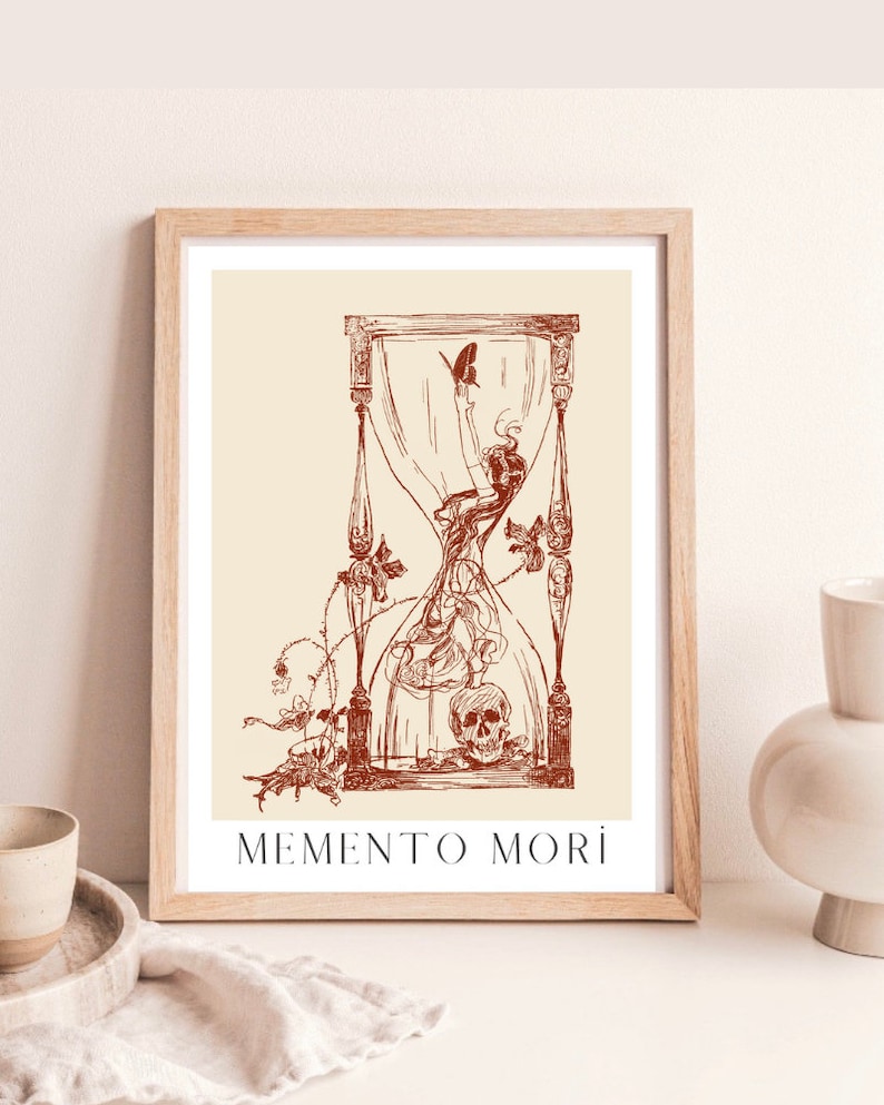 May include: A framed print featuring a red hourglass design. The hourglass is filled with a swirling, smoke-like substance and a skull at the bottom. The text "MEMENTO MORI" is printed below the hourglass.