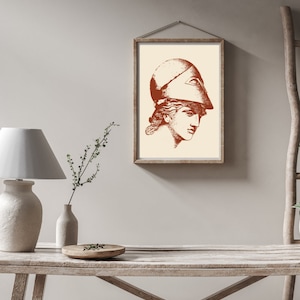 May include: A framed print of a woman's head wearing a helmet. The print is in shades of brown and white and is set against a light beige wall.