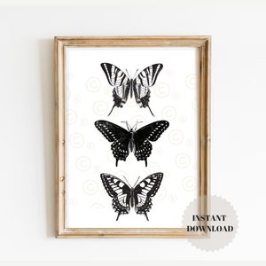 May include: A printable art print featuring three black and white illustrations of butterflies. The butterflies are arranged vertically, with the largest butterfly at the top and the smallest butterfly at the bottom. The background is a light cream color with a subtle pattern of circles.