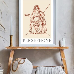 May include: A vintage illustration of Persephone, the Greek goddess of spring, in a seated pose. She is holding a bowl in her left hand and a staff in her right hand. The illustration is in a brown color and is framed in a white frame.