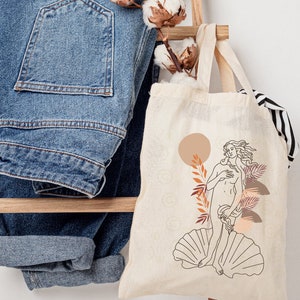 Peut inclure: Un sac fourre-tout beige avec un dessin au trait d'une femme debout sur une coquille Saint-Jacques. La femme est entour&eacute;e de feuilles stylis&eacute;es et d'un cercle couleur p&ecirc;che. Le texte "THERE WON'T BE A COPYRIGHT MARK ON YOUR BAG" est en bas de l'image.
