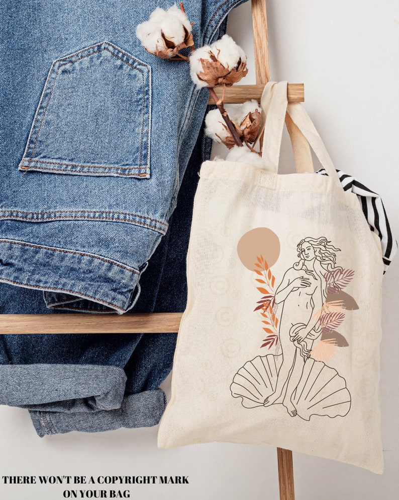 Peut inclure: Un sac fourre-tout beige avec un dessin au trait d'une femme debout sur une coquille Saint-Jacques. La femme est entour&eacute;e de feuilles stylis&eacute;es et d'un cercle couleur p&ecirc;che. Le texte "THERE WON'T BE A COPYRIGHT MARK ON YOUR BAG" est en bas de l'image.