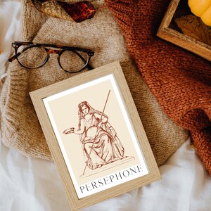 May include: A framed print of a line drawing of Persephone, the Greek goddess of spring, in a seated pose. The print is on a cream background with the word "PERSEPHONE" in red lettering at the bottom.