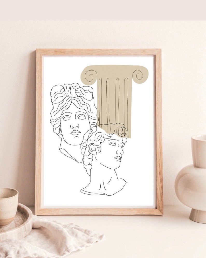 May include: Line art print of two classical busts with a beige column behind them. The print is framed in a light wood frame.
