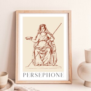 May include: A vintage illustration of Persephone, the Greek goddess of spring, in a red-brown color scheme. She is depicted wearing a crown and holding a bowl and a staff. The image is framed in a light wood frame.