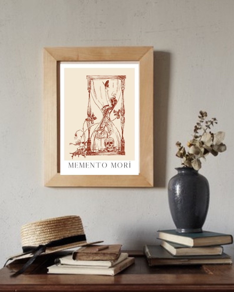 May include: A framed print featuring a brown hourglass with a skull at the base and a butterfly flying above. The print includes the text "MEMENTO MORI" at the bottom.