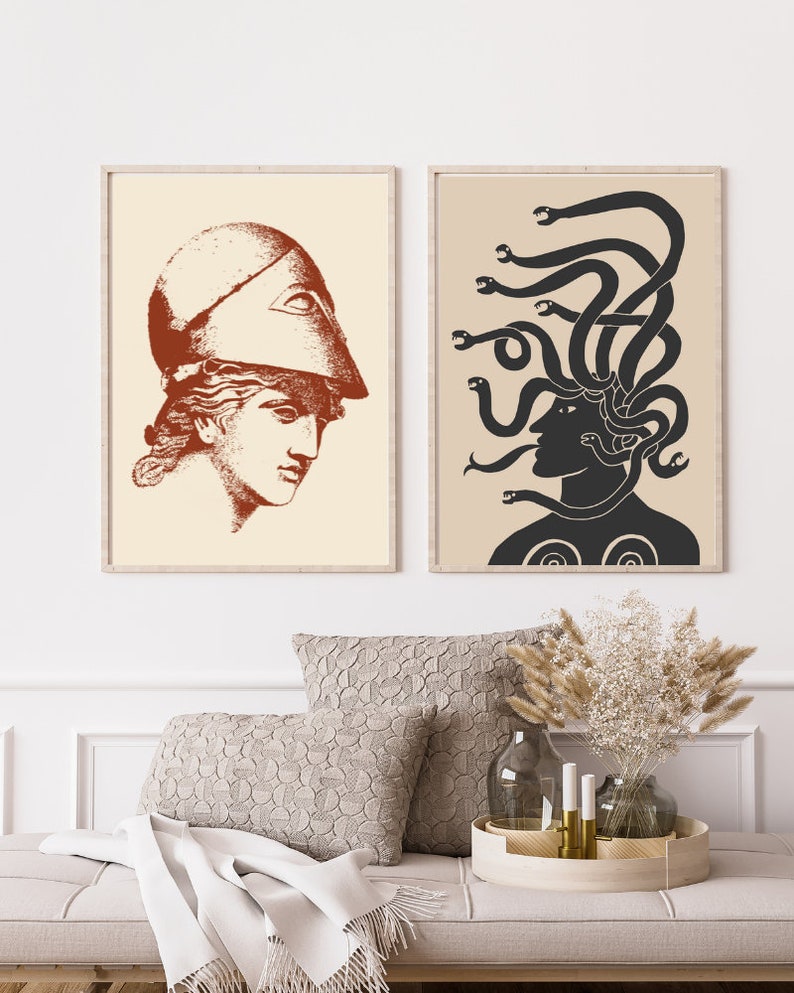 May include: Two framed prints with a minimalist design. The print on the left features a woman's head in profile wearing a helmet with a single eye. The print on the right features a woman's head in profile with snakes for hair. Both prints are in shades of brown and black on a cream background.