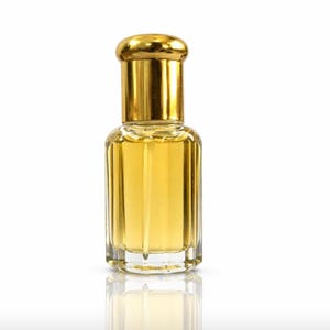 May include: A small, clear glass perfume bottle with a gold-coloured cap. The bottle is filled with a golden-yellow liquid. The bottle has vertical ridges and a rounded base. The cap is a shiny gold colour.