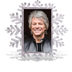 May include: A clear, snowflake-shaped photo frame with a rectangular aperture. The frame holds a portrait of a smiling person with grey hair, wearing a black leather jacket. The frame casts a shadow.