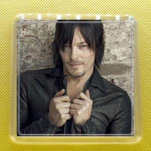 May include: A close-up portrait of a man with dark hair and a leather jacket. He is looking at the camera with a serious expression.