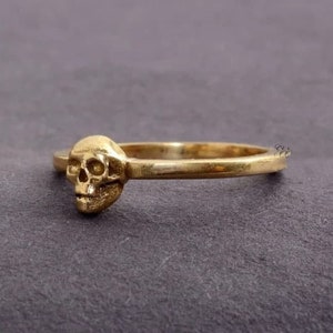 May include: A gold skull ring with a simple band.