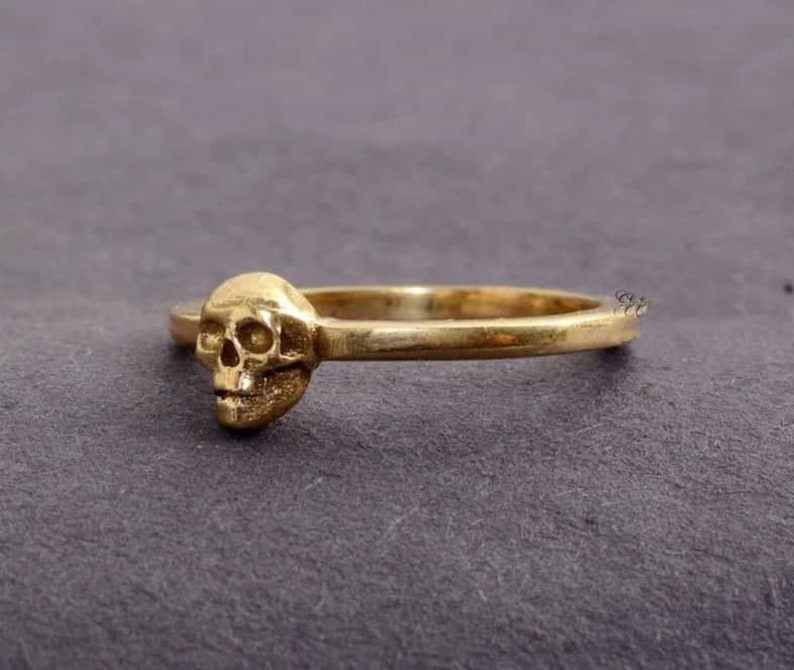 May include: A gold skull ring with a simple band.