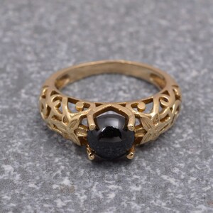 May include: A gold ring with a black gemstone set in a delicate filigree design.