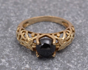 May include: A gold ring featuring a black gemstone set in a delicate filigree design.