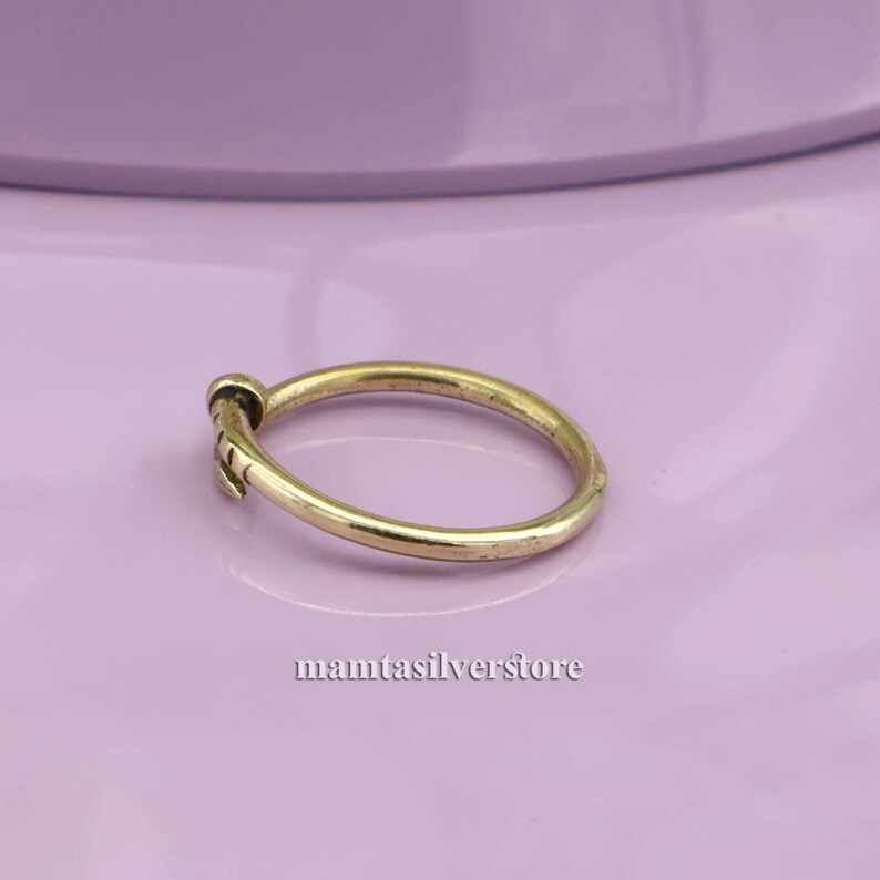 May include: A simple gold band ring with a small, textured design on the side.