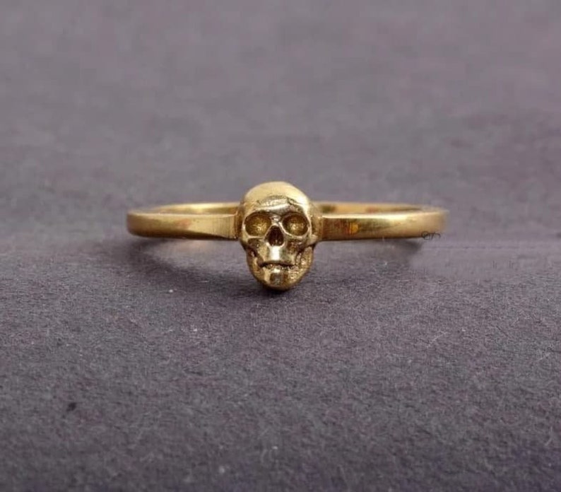 May include: A gold skull ring with a simple band.