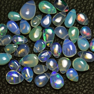 May include: A collection of iridescent white opal teardrop cabochons. The opals have a variety of colors, including blue, green, and red.
