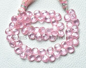 May include: A strand of pink gemstone beads, each bead is faceted and has a round shape. The beads are strung on a thin cord with a pink tassel at one end. The beads are arranged in a loose circle, and the tassel is hanging down.