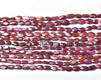 Puede incluir: Una hebra de cuentas de piedras preciosas facetadas de color rojo púrpura. Las cuentas son de forma ovalada y tienen un acabado liso y pulido.