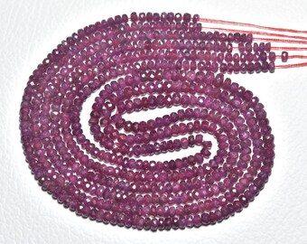 May include: Strands of faceted, deep magenta-colored gemstone beads. The beads are strung together, forming a spiral pattern. The beads are small and uniform in size, with a polished, reflective surface. The overall effect is one of rich color and texture.
