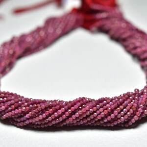 Puede incluir: Una hebra de cuentas de rubí rosa, facetadas y enhebradas. Las cuentas son pequeñas y de tamaño uniforme, creando un aspecto delicado y elegante.