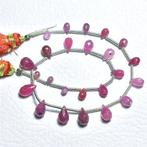 May include: A strand of pink and red gemstone beads in a teardrop shape. The beads are strung on a silver wire and are ready to be used for jewellery making.