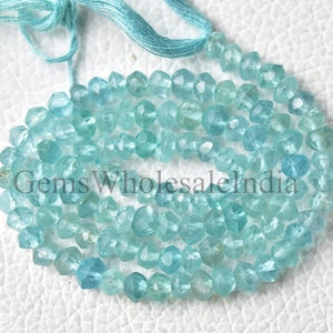 May include: A strand of light blue faceted gemstone beads. The beads are small and have a slightly irregular shape. The beads are strung on a thin blue thread.