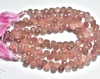 May include: A strand of pink rose quartz beads, with a faceted, irregular shape. The beads are strung on a clear cord and have a pink tassel at each end.