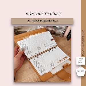 May include: A monthly tracker for a planner, printed on white paper with black ink. The tracker is designed for a A5 ring planner. The tracker is in a brown leather planner with gold rings. The tracker has a grid pattern and is labeled with the days of the week. The tracker is labeled "Monthly Tracker" and "A5 Rings Planner Size".