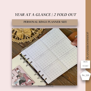 Peut inclure: Insert de planificateur personnel avec une présentation annuelle. Le document présente une conception dépliante en 2 parties avec des grilles de calendrier pour chaque mois. Le texte "YEAR AT A GLANCE / 2 FOLD OUT" et "PERSONAL RINGS PLANNER SIZE" sont visibles.